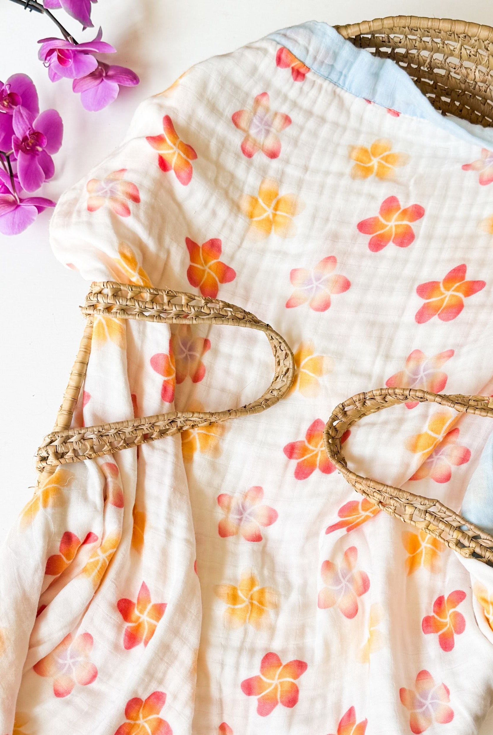 organic tropical flower print double sided baby blanket. Blue trim with colorful plumeria flowers