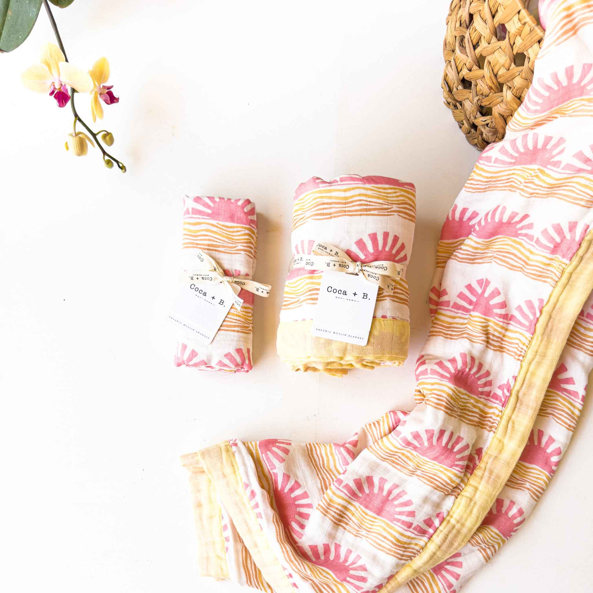 Pink and yellow patterned fabric with rolled-up swaddles on a white background
