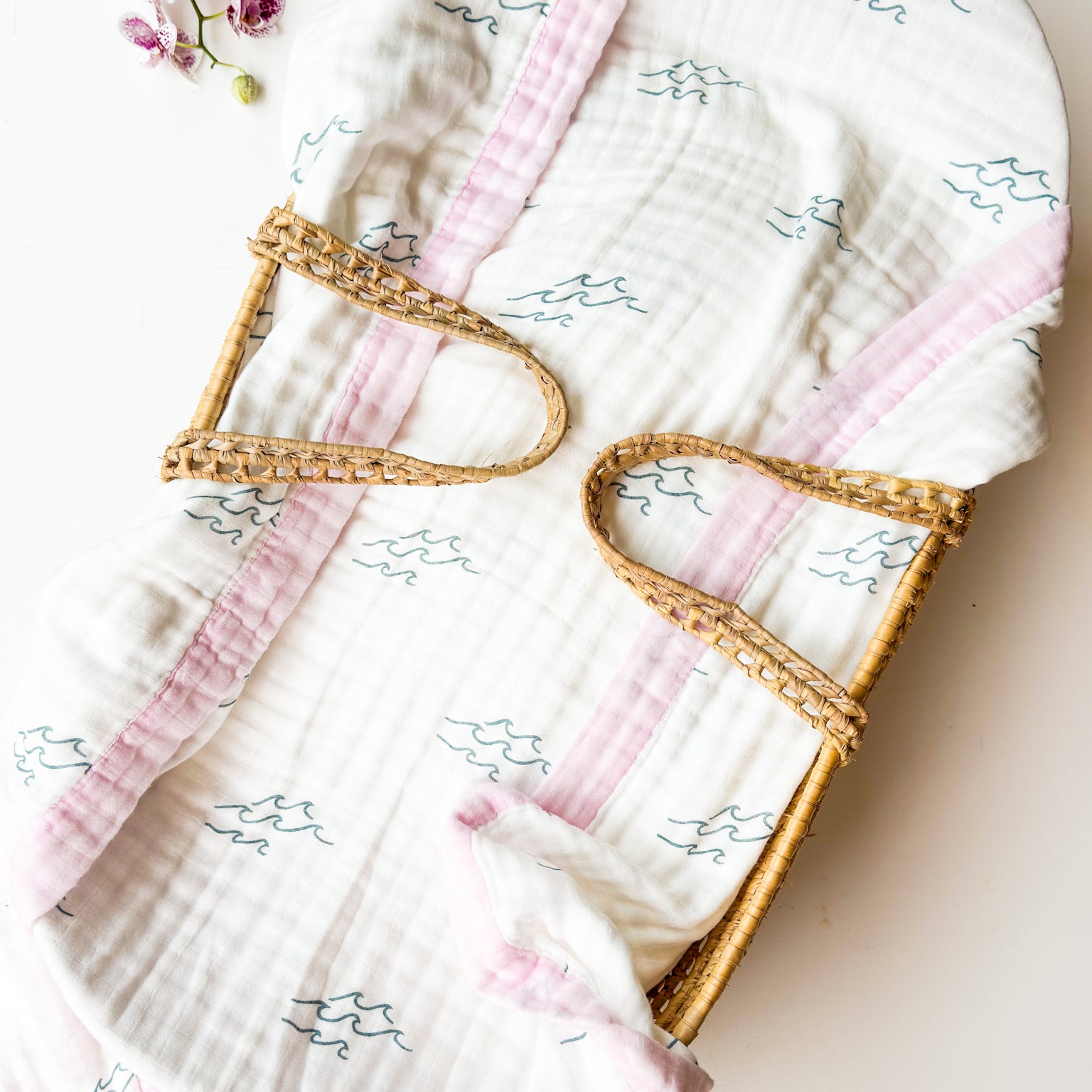Baby blanket with pink trim and wave design on a light background