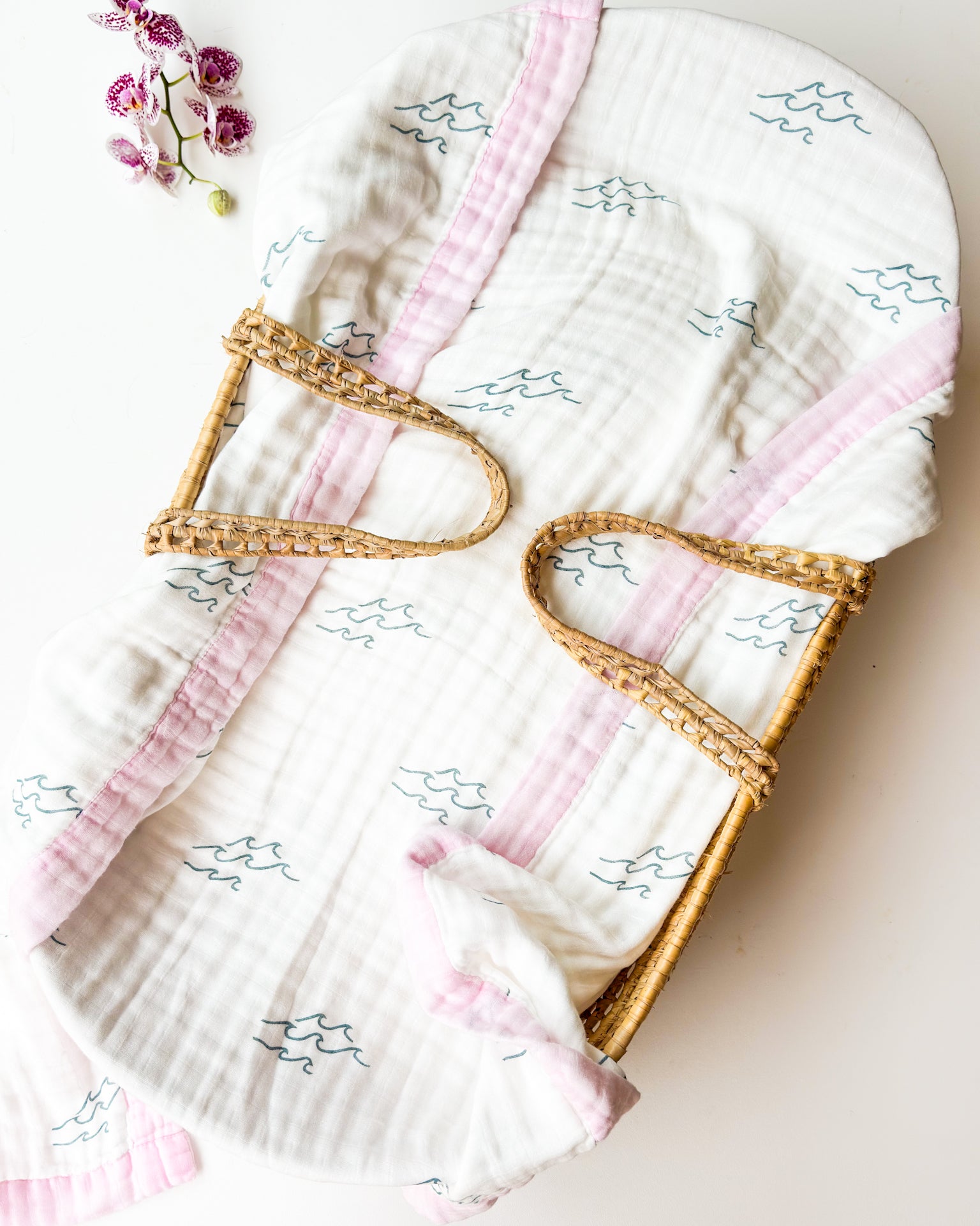 Baby blanket with pink trim and wave design on a light background