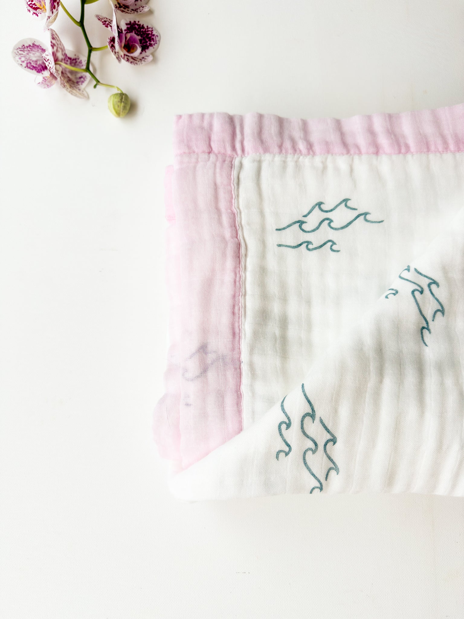 Baby blanket with wave patterns and pink trim on a white background