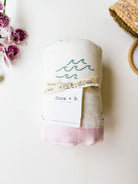Coca+B. blanket with wave print and pink trim and woven basket background