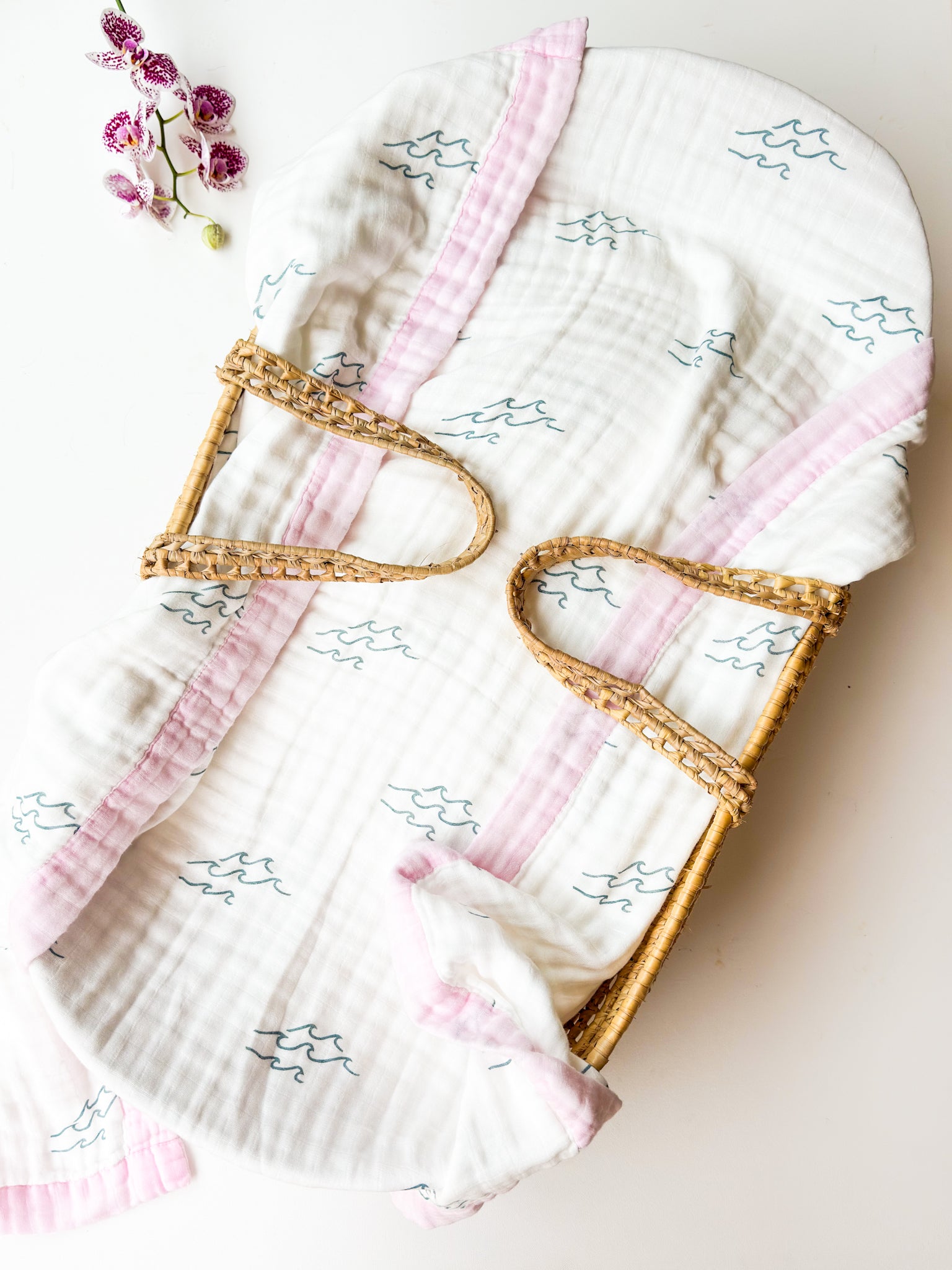 Baby blanket with pink trim and wave design on a light background