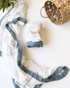 Baby blanket with wave print and with blue trim and white label on a light surface